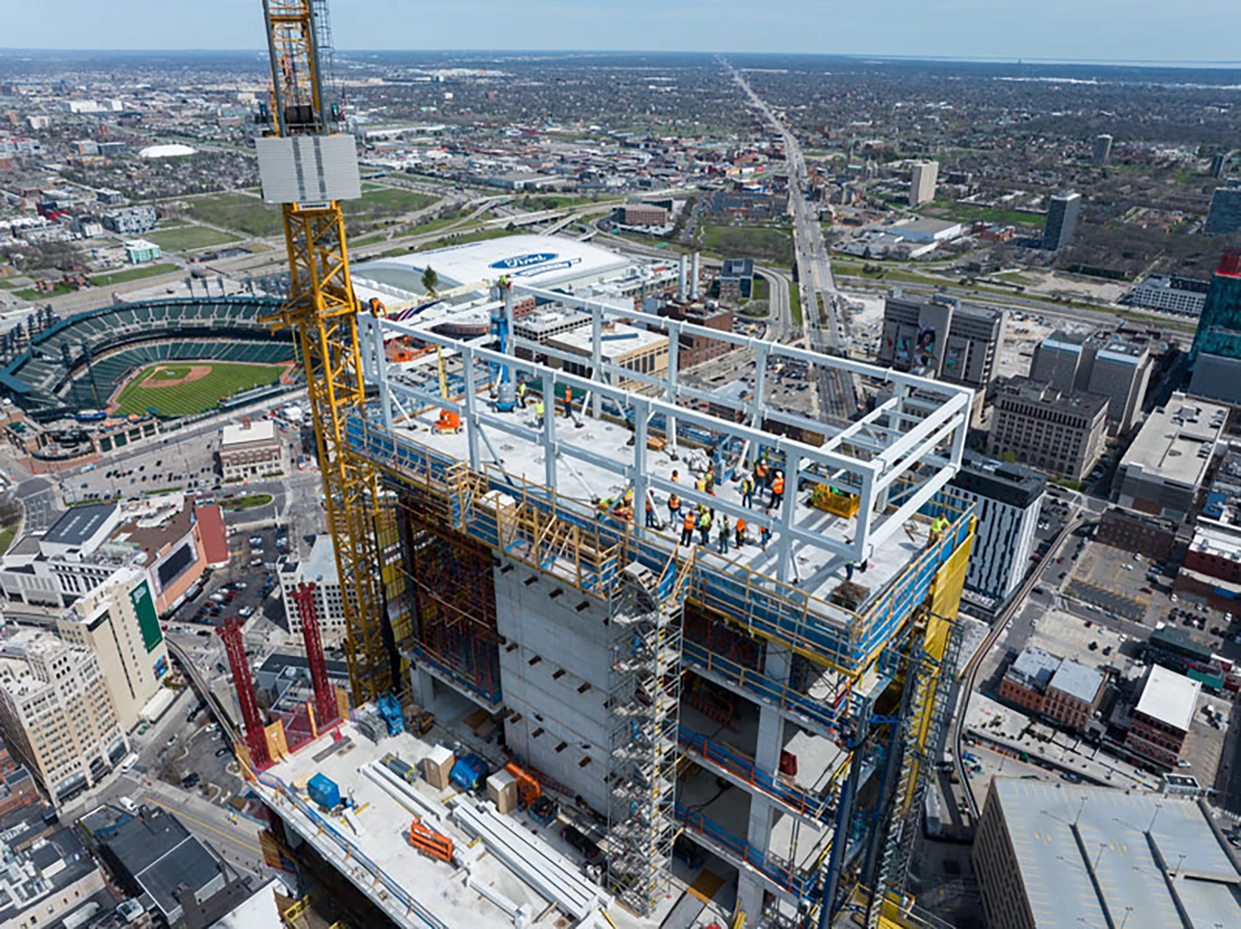 High-rise construction site with crews working atop a steel-framed structure, illustrating large-scale commercial electrical and construction coordination.