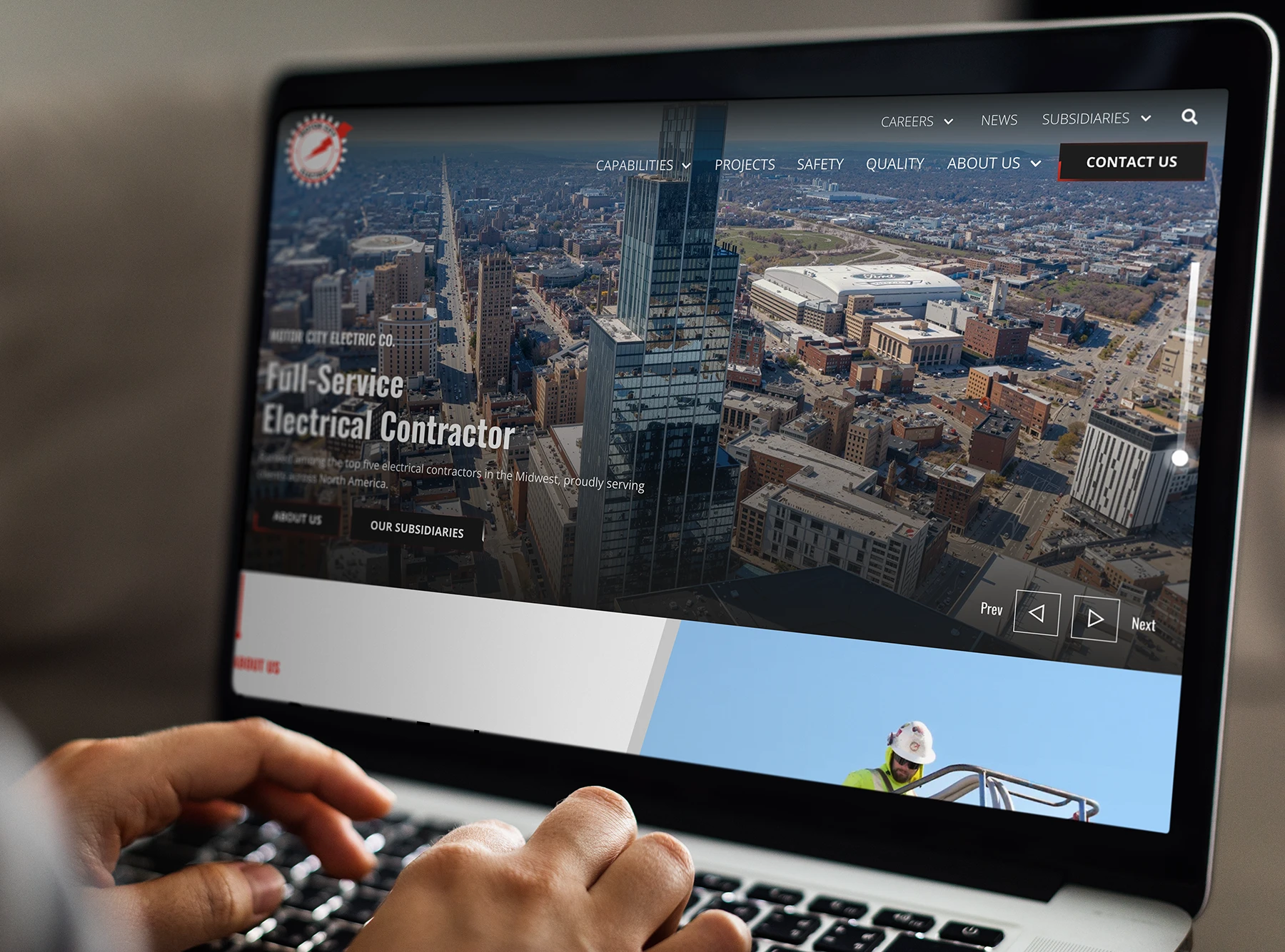 Motor City Electric website displayed on a laptop, featuring an aerial cityscape and full-service electrical contractor messaging.